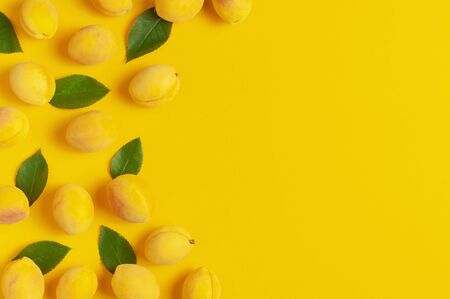Ripe fresh apricots fruits with green leaves on yellow background. Flat lay, top view, copy space. Fresh organic apricots, diet vegan food. Creative Apricot pattern. Harvest concept.の写真素材