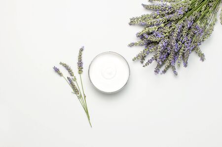Concept of natural spa cosmetics. Open jar of hand, face or body cream and bouquet of lavender on white background top view copy space. Natural herbal skin care products.の写真素材