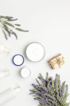 Concept of natural spa cosmetics. Open jar of hand, face or body cream, white cosmetics bottles, soap and lavender on white background top view copy space. Natural herbal skin care products.の写真素材