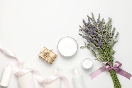 Concept of natural spa cosmetics. Open jar of hand, face or body cream, white cosmetics bottles, soap and lavender on white background top view copy space. Natural herbal skin care products.の写真素材