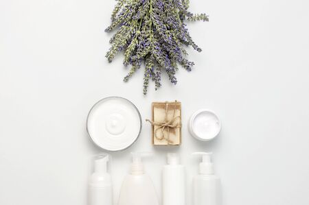 Concept of natural spa cosmetics. Open jar of hand, face or body cream, white cosmetics bottles, soap and lavender on white background top view copy space. Natural herbal skin care products.の写真素材