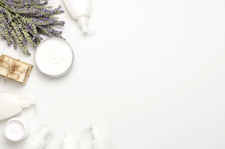 Concept of natural spa cosmetics. Open jar of hand, face or body cream, white cosmetics bottles, soap and lavender on white background top view copy space. Natural herbal skin care products.の写真素材