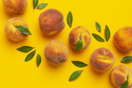 Flat lay composition with peaches. Ripe juicy peaches with green leaves on yellow background. Flat lay, top view, copy space. Fresh organic fruit, vegan food. Harvest concept.の写真素材