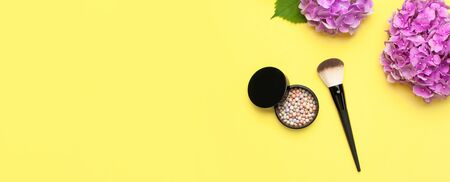 Set of decorative cosmetics makeup brushes, blush face balls, pink hydrangea flowers on yellow background top view Flat lay copy space. Beauty blogger concept. Fashion background. Makeup accessories.の写真素材