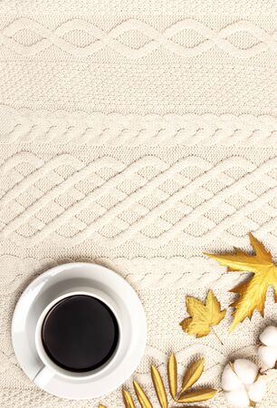 Flat lay autumn composition. Cup of coffee, knitted woolen light beige sweater or plaid, golden dry leaves, cotton flowers top view copy space. Autumn, fall concept. Cozy lifestyle details.の写真素材