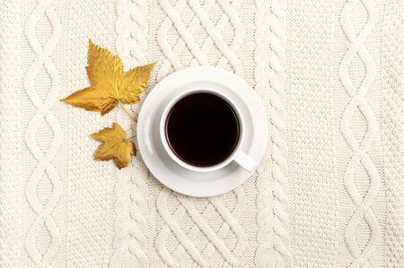 Flat lay autumn composition. Cup of coffee, knitted woolen light beige sweater or plaid, golden dry leaves top view copy space. Autumn, fall concept. Cozy lifestyle details.の写真素材