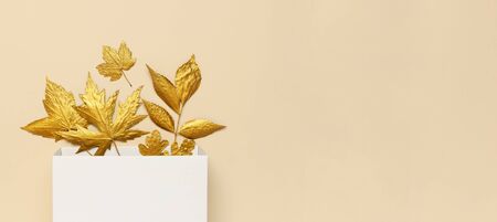Flat lay creative autumn composition. White Gift Paper package and Golden leaves on beige background top view copy space. Fall concept. Autumn background. Minimal concept idea, floral design.の写真素材