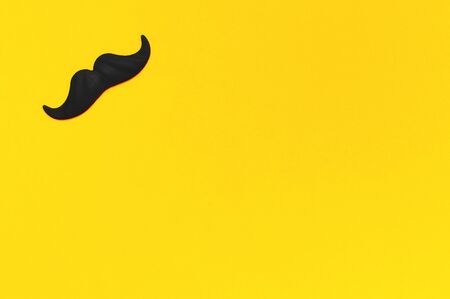Creative party decoration concept. Black mustache, props for photo booths, carnival parties on yellow background top view flat lay copy space Father's day Men's health awareness month.の写真素材