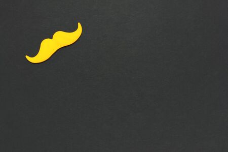 Creative party decoration concept. Yellow mustache, props for photo booths, carnival parties on black background top view flat lay copy space Father's day Men's health awareness month.の写真素材