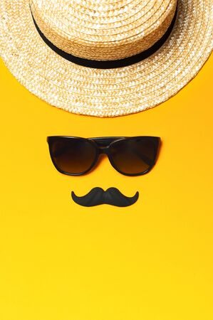 Creative party decoration concept. Black mustache, sunglasses, straw hat, carnival parties on yellow background top view flat lay copy space. Father's day Men's health awareness month.の写真素材