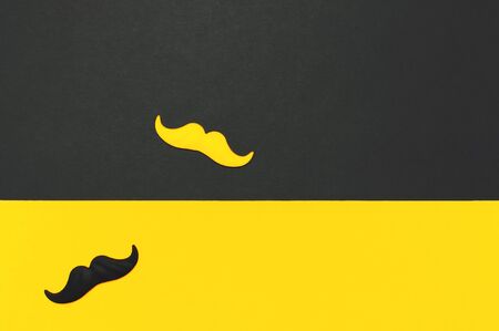 Creative party decoration concept. Black and yellow mustache, props for photo booths, carnival parties on black yellow background top view flat lay copy space Father's day Men's health awareness month.の写真素材