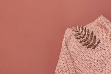 Flat lay autumn composition. Knitted woolen pink female sweater or plaid, golden dry leaves on burgundy brown background top view copy space. Fall concept. Fashion color, cozy autumn thing, clothes.の写真素材