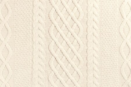The texture of beige sweater pullover. Knitted background. Knitted texture. A sample of knitting from wool. Handmade sweater texture, knitted wool pattern.の写真素材