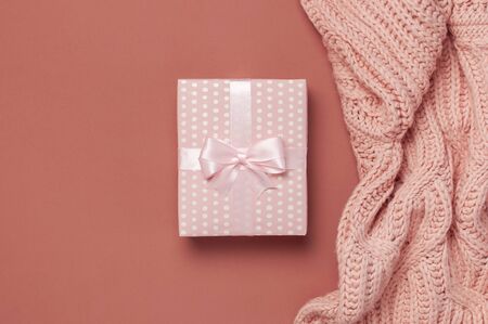 Flat lay autumn composition. Knitted woolen pink female sweater or plaid, pink gift with ribbon on burgundy brown background top view copy space. Autumn gift fall concept. Fashionable women's clothing.の写真素材