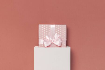 Pink gift or present box with festive pink ribbon on burgundy brown background top view copy space. Autumn gift, fall concept. Flat lay composition for birthday, mother day, Valentine's Day, wedding.の写真素材