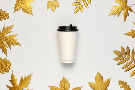 Coffee or tea paper cup, golden autumn leaves on light gray background top view flat lay. Take away coffee cup, mockup. Coffee love, layout for design. Fall concept. Autumn background. Copy space.の写真素材