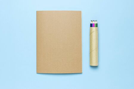 Color pencils and clean notebook in line on blue background top view flat lay copy space. Wooden colored pencils for drawing, objects for creativity, school supplies close-up. Back to school concept.の写真素材