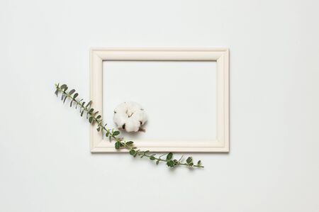 White wooden photo frame and spring green twigs of plants on gray background. Flat lay top view copy space. Stylish minimal composition, artwork mockup, picture frame, home decoration.の写真素材