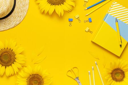 Top view flat lay of workspace desk styled design with sunflowers, straw hat, notebook, diary, pencils, pen scissors on bright yellow background. Autumn or summer Concept. Sunflower natural background.の写真素材