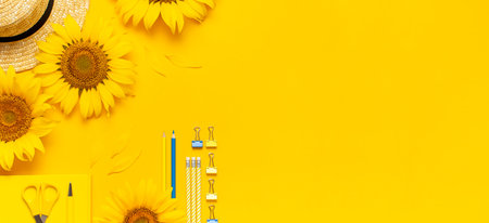Top view flat lay of workspace desk styled design with sunflowers, straw hat, notebook, diary, pencils, pen scissors on bright yellow background. Autumn or summer Concept. Sunflower natural background.の写真素材