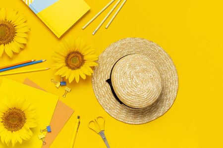 Top view flat lay of workspace desk styled design with sunflowers, straw hat, notebook, diary, pencils, pen scissors on bright yellow background. Autumn or summer Concept. Sunflower natural background.の写真素材