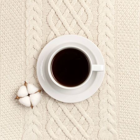 Flat lay autumn composition. Cup of coffee, knitted woolen light beige sweater or plaid, cotton flowers top view copy space. Autumn, fall concept. Cozy lifestyle details.の写真素材