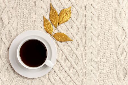 Flat lay autumn composition. Cup of coffee, knitted woolen light beige sweater or plaid, golden dry leaves top view copy space. Autumn, fall concept. Cozy lifestyle details.の写真素材