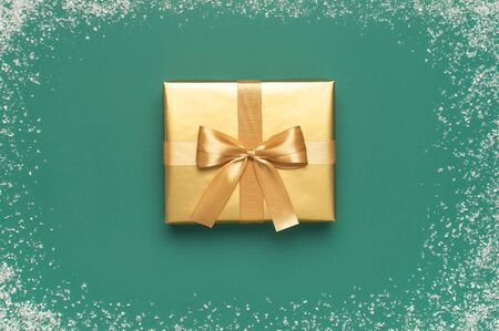 New Year Christmas presents, golden gift with holiday ribbon on green background with snow frame top view. Flat lay Xmas holiday 2020 celebration. Gift boxes greeting card Festive decorations.の写真素材