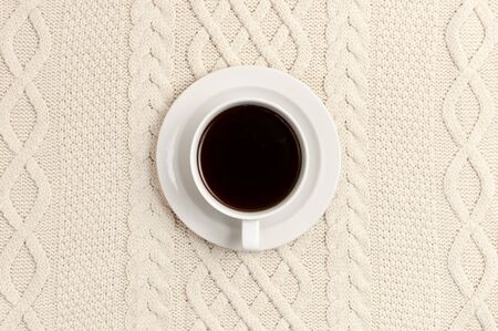 Flat lay autumn composition. Cup of coffee on a background of knitted beige woolen sweater or plaid top view copy space. Autumn, fall concept. Cozy lifestyle details.の写真素材