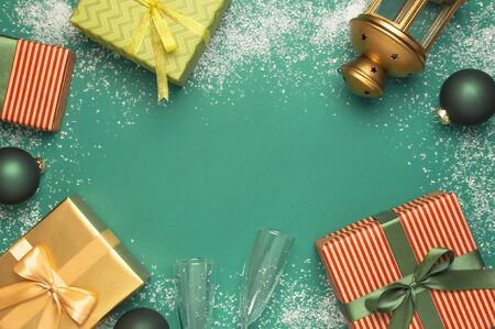 New Year Christmas presents, Christmas balls, champagne glasses, gold confetti stars on green background top view. Flat lay Xmas holiday 2020 celebration. Gift boxes greeting card Festive decorations.の写真素材