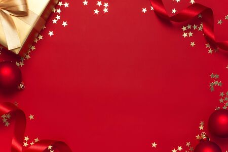 New Year Christmas golden presents with ribbon, Christmas balls, gold confetti stars on red background top view. Flat lay Xmas holiday 2020 celebration. Gift boxes greeting card Festive decorations.の写真素材