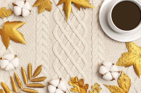 Flat lay autumn composition. Cup of coffee, knitted woolen light beige sweater or plaid, golden dry leaves, cotton flowers top view copy space. Autumn, fall concept. Cozy lifestyle details.の写真素材