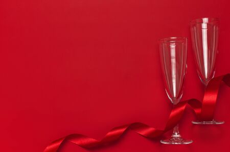 Champagne glasses and festive ribbon on red background top view copy space. Flat lay Xmas holiday 2020 celebration. Creative composition, concept of firework holiday party birthday New Year Christmas.の写真素材