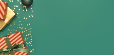 New Year Christmas presents with green ribbon, Christmas balls, gold confetti stars on green background top view. Flat lay Xmas holiday 2020 celebration. Gift boxes greeting card Festive decorations.の写真素材