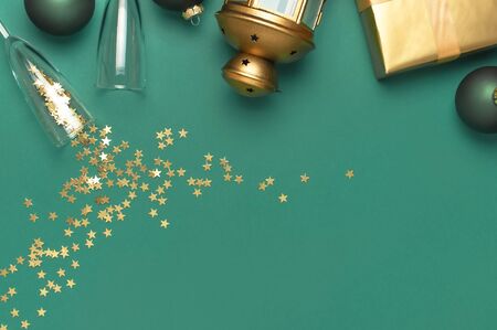 New Year Christmas presents, Christmas balls, champagne glasses, gold confetti stars on green background top view. Flat lay Xmas holiday 2020 celebration. Gift boxes greeting card Festive decorations.の写真素材