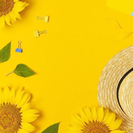 Top view flat lay of workspace desk styled design with sunflowers, straw hat, notebook, diary, pencils, pen scissors on bright yellow background. Autumn or summer Concept. Sunflower natural background. Square formatの写真素材