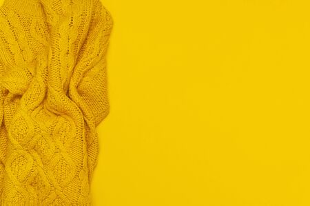 Autumn flat lay composition. Orange yellow knitted woolen female sweater on yellow background top view copy space. Fashionable women's fall winter accessories. Cozy Knit Jumper Stylish Lady Clothes.の写真素材
