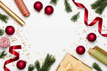 Flat lay Xmas holiday 2020 celebration. New Year Christmas golden presents with ribbon red Christmas balls pine branches gold confetti stars on gray background top view. Gift boxes Festive decorations.の写真素材