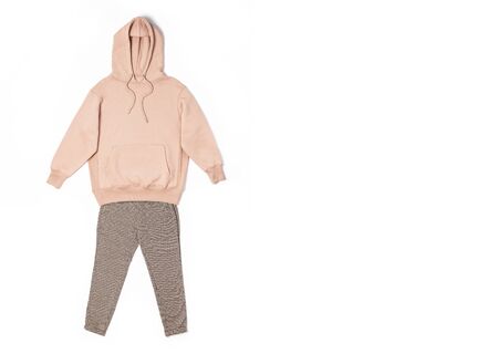 Female peach pink sweatshirt with pocket and hood, pants in classic pattern isolated on white background. Fashionable women's clothing, hoody, casual youth style, sports. Autumn fashion.の写真素材