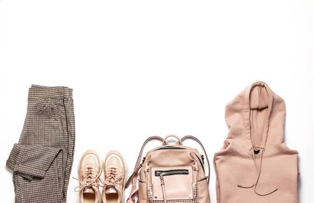 Female peach pink sweatshirt with pocket and hood, pants in classic pattern, sneakers, backpack isolated on white background. Fashionable womens clothing, hoody, casual youth style, sports.の写真素材