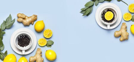 Creative food concept. Fresh ginger root, cup tea with brewing inside, lemon, eucalyptus leaves on blue background. Flat lay top view copy space. Minimalistic style seasoning spice ingredient for tea.の写真素材