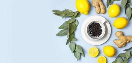 Creative food concept. Fresh ginger root, cup tea with brewing inside, lemon, eucalyptus leaves on blue background. Flat lay top view copy space. Minimalistic style seasoning spice ingredient for tea.の写真素材