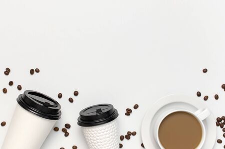 Coffee or tea paper cup, white cup with coffee, coffee beans on light gray background top view flat lay copy space. Take away coffee cup, mockup. Minimal composition, layout for design.の写真素材