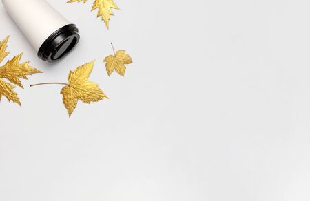 Coffee or tea paper cup, golden autumn leaves on light gray background top view flat lay. Take away coffee cup, mockup. Coffee love, layout for design. Fall concept. Autumn background. Copy space.の写真素材