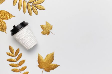 Coffee or tea paper cup, golden autumn leaves on light gray background top view flat lay. Take away coffee cup, mockup. Coffee love, layout for design. Fall concept. Autumn background. Copy space.の写真素材