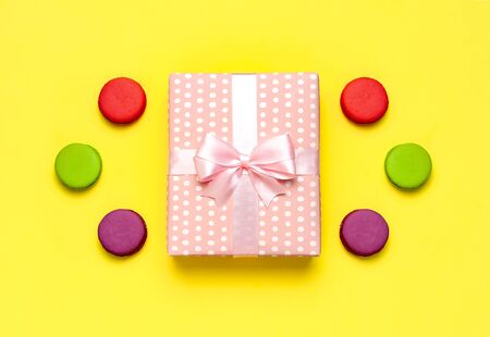 Gift or present box, or macaroon on yellow background top view. Creative Flat lay composition for celebration, holiday, birthday, Valentine's Day, March 8, mother day, wedding.の写真素材