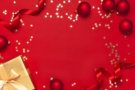 New Year Christmas golden presents with ribbon, Christmas balls, gold confetti stars on red background top view. Flat lay Xmas holiday 2020 celebration. Gift boxes greeting card Festive decorations.の写真素材