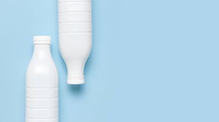 White plastic bottle containers for dairy products on blue background top view flat lay. Plastic Kefir Yogurt Milk Bottle. Packaging template mockup. Layout for your design.の写真素材