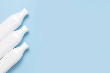 White plastic bottle containers for dairy products on blue background top view flat lay. Plastic Kefir Yogurt Milk Bottle. Packaging template mockup. Layout for your design.の写真素材