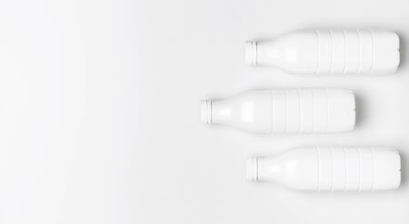 White plastic bottle containers for dairy products on light gray background top view flat lay. Plastic Kefir Yogurt Milk Bottle. Packaging template mockup. Layout for your design.の写真素材